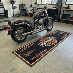 Harley Davidson motorcycle in a garage with a branded mat on the floor.