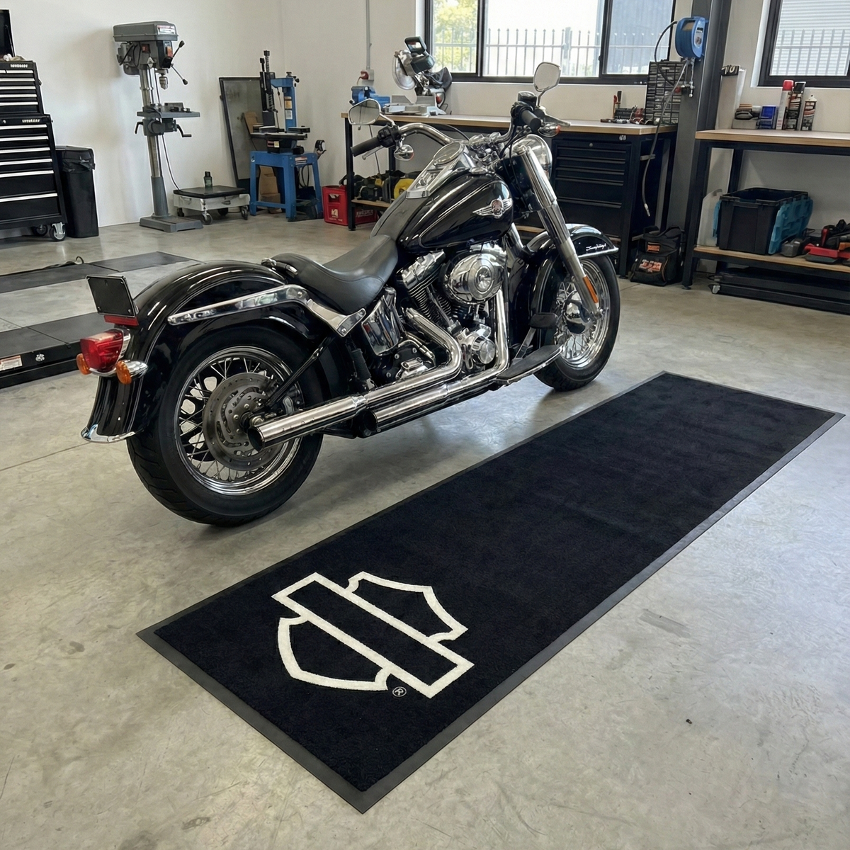 Motorcycle on a black mat with a logo in a garage setting