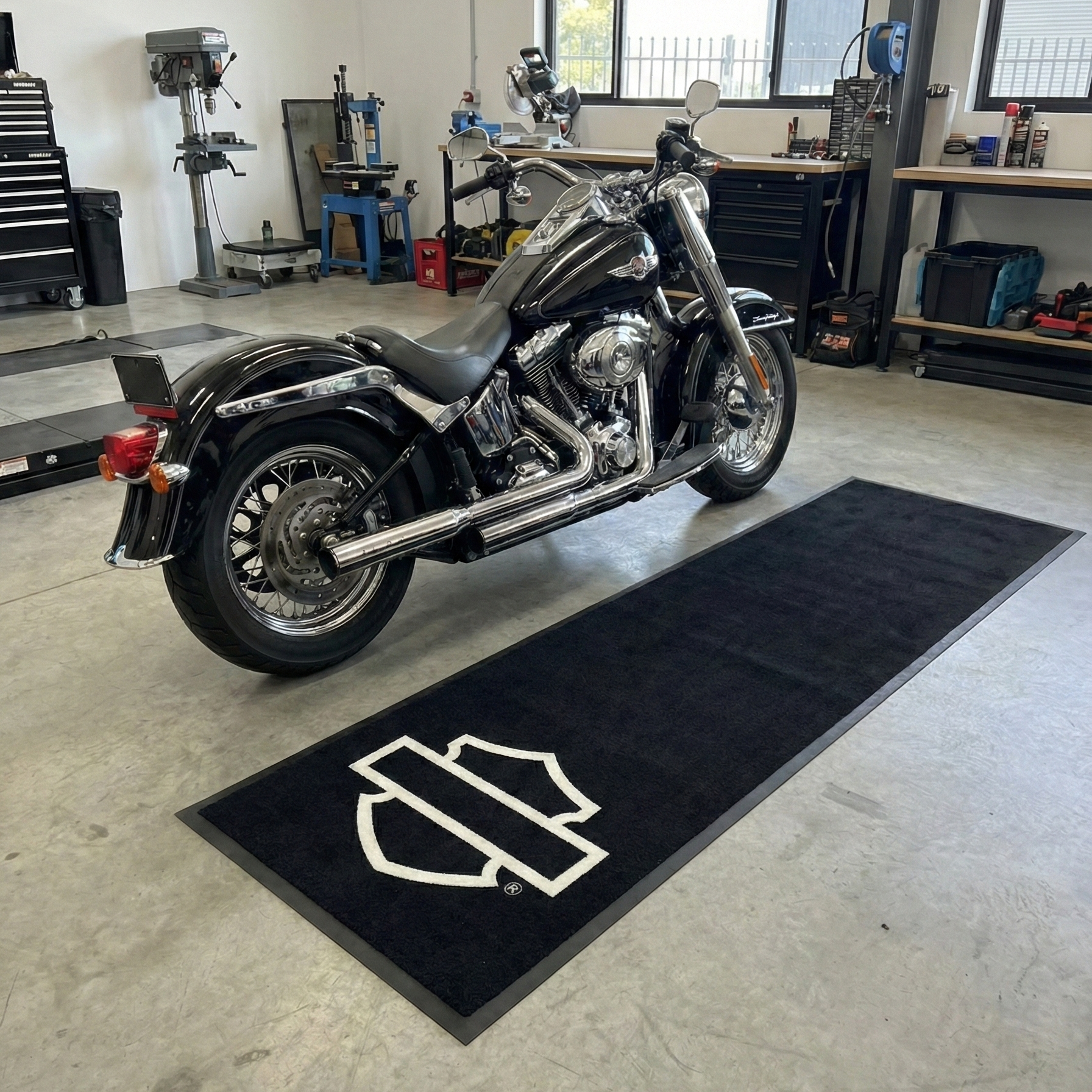 Motorcycle on a black mat with a logo in a garage setting